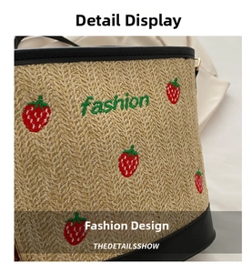 Close-up of straw bucket bag with red strawberry embroidery and black leather trim