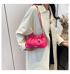 Dettaglio di borsa a spalla rosa trapuntata con bordi a pieghe e placca logo dorata