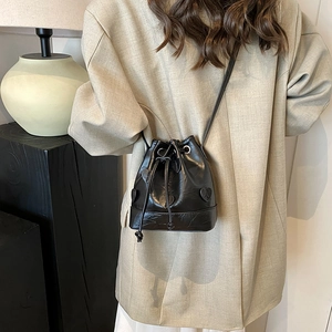 Minimalist black drawstring bucket bag with heart appliques shown on a model's shoulder