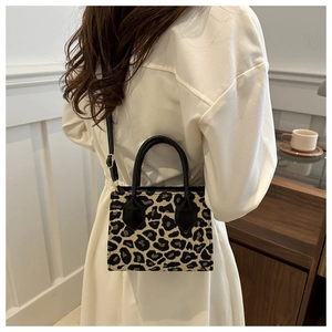 Detail of leopard print mini crossbody bag with black leather handles and gold hardware