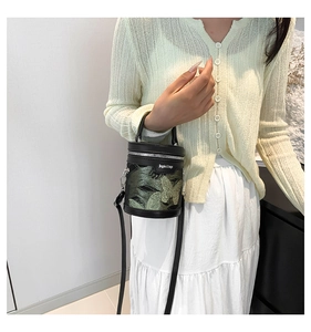 Dettaglio di una mini borsa a secchiello con ricamo a farfalla verde e cerniera argento