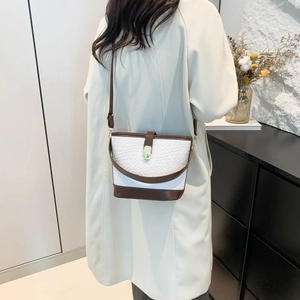 Fashionable woven bucket bag with brown leather trim and golden buckle on model