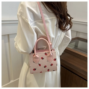Detail of pink strawberry print tote bag shown from a cross-body back view perspective