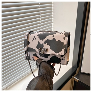 Gros plan du sac à main à motif vache noir et blanc avec chaîne et fermoir en métal gris