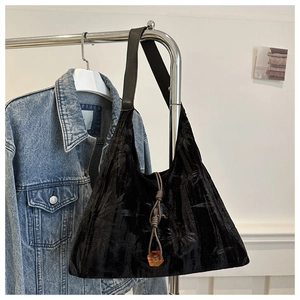 Detail of black velvet tote bag with leaf embossing and amber cube charm accent