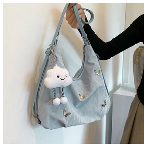 Gros plan du sac fourre-tout en nylon bleu clair avec papillon argenté et breloque nuage