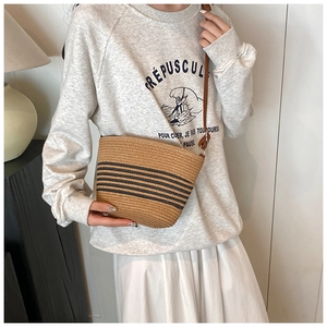 French style woven straw bucket bag featuring contrast stripes and leather shoulder strap