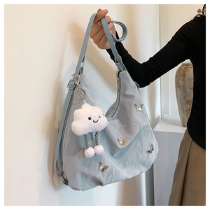 Détail du sac demi-lune bleu clair avec breloques papillon et pendentif en peluche
