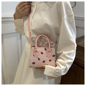 Detailed shot of pink corduroy crossbody bag with strawberry embroidery and leather handles