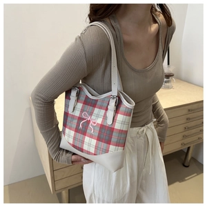 Détail d'un sac cabas à carreaux avec broderie ruban porté par un mannequin en intérieur