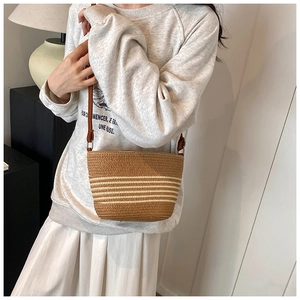 Détail d'un sac seau en paille avec rayures marron et blanc sur texture tressée