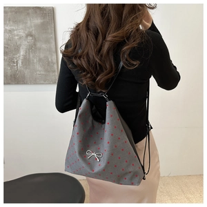 Détail du sac à dos gris à pois avec nœud argenté porté par un mannequin femme