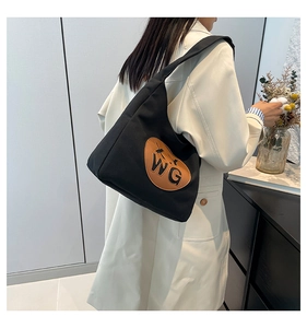 Detail of black canvas tote bag with brown WG leather patch and wide shoulder strap