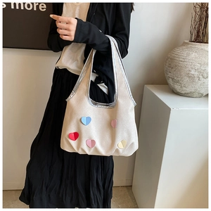 Detail der cremeweißen Canvas-Tasche mit Metallic-Besatz und fünf bunten 3D-Herzen