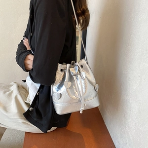 Silver metallic drawstring bucket bag with heart appliques and pleated texture