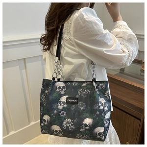 Détail du sac cabas en toile avec motifs têtes de mort, fleurs et sangle à chaîne métal