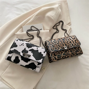 Fashionable chain shoulder bags with trendy leopard and cow prints on a soft cream blazer