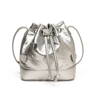 Silver metallic drawstring bucket bag with heart patch details and wrinkled texture