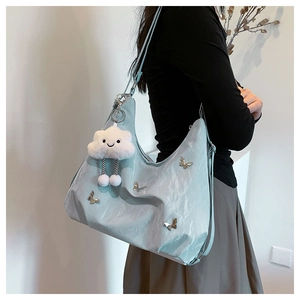 Détail du sac croissant bleu clair avec décor papillon et pendentif nuage en peluche