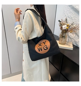 Close-up of black canvas tote bag featuring a brown leather patch with X.Y WG logo lettering