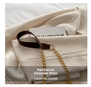 Detail of the brown leather shoulder strap with gold metal rings and thick chain link
