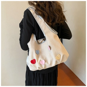 Detailansicht bunter Herzaufnäher auf minimalistischer weißer Canvas-Schultertasche