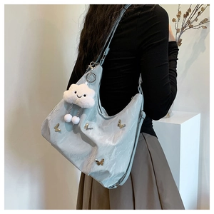 Détail du grand sac croissant avec papillon en métal et breloque nuage sur le mannequin
