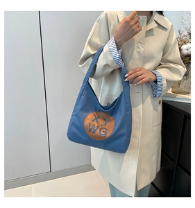 Close-up of large canvas tote bag with embossed letter patch and leather details