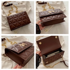 Detail view of brown quilted bag with gold butterfly metal buckle and chain strap