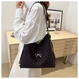 Détail d'un sac cabas en toile noire avec motifs cœurs rouges et nœud argenté décoratif