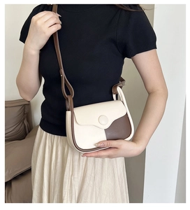 Close-up of a two-tone crossbody square bag in cream and dark brown leather on model