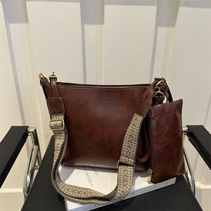 Vintage brown leather bucket bag with ethnic strap and small pouch on white book