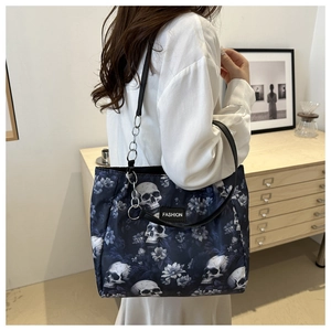 Détail du sac cabas bleu avec crânes blancs, imprimés floraux et étiquette logo fashion
