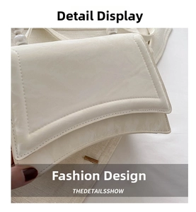 Detail of white glossy flap bag showing pearl handle and dual stitching craftsmanship