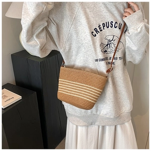 Détail d'un sac à bandoulière en paille tressée avec rayures blanches et cuir