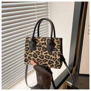 Detailed view of leopard print square handbag with black leather handles and shoulder strap