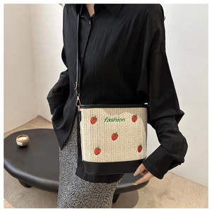 Side view of woven bucket bag with strawberry embroidery and adjustable shoulder strap