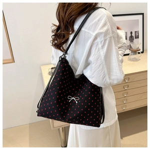 Détail du sac cabas noir avec motifs de cœurs rouges et boucle de nœud argentée