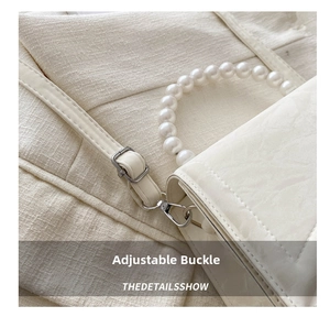 Detail view of the silver adjustable buckle and white pearl handle of the handbag