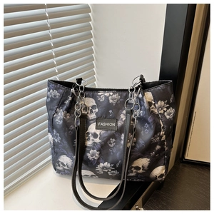 Detail of fashion tote bag featuring skull and floral prints with metallic chain handle