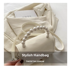 Close-up of white crossbody bag featuring elegant large pearl handle and matte leather texture