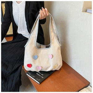 Detailaufnahme der cremefarbenen Canvas-Tasche mit bunten Herz-Patches und silbernem Rand