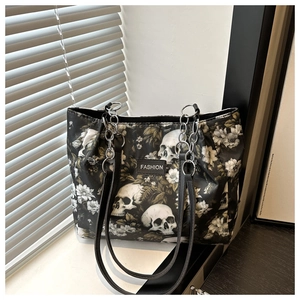 Detail of a large black tote bag with skull and floral print and silver chain strap