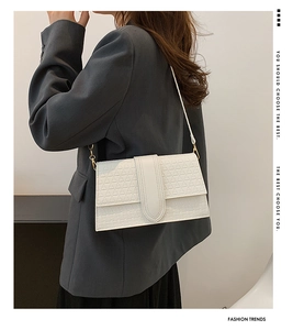 Detail of white crossbody bag with geometric triangle texture and modern flap design