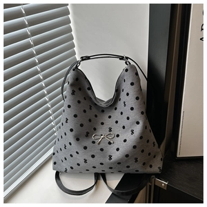 Détail du sac cabas gris à pois avec breloque nœud argenté et fines anses en cuir