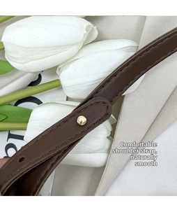 Detail of brown leather shoulder strap with gold rivet and fine stitching craftsmanship