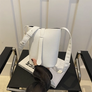 Minimalist white litchi pattern leather bucket bag shown in a stylish modern indoor setting