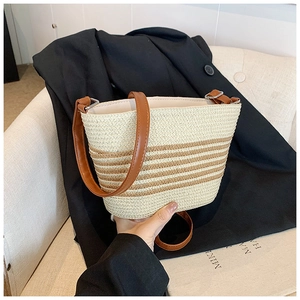 Detail of adjustable leather strap and striped straw weave texture of bucket bag