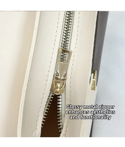 Close-up of smooth gold metal zipper and stitching on beige leather crossbody bag
