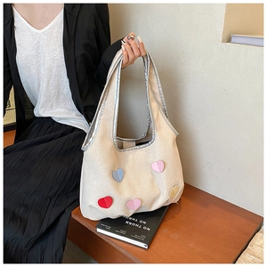 Canvas-Tragetasche mit bunten Herz-Patches, gehalten in einem minimalistischen Raum